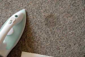 Use an iron and a paper towel to extract wax from carpet fibers.