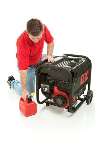 Man holding a small portable fuel tank beside an emergency generator.