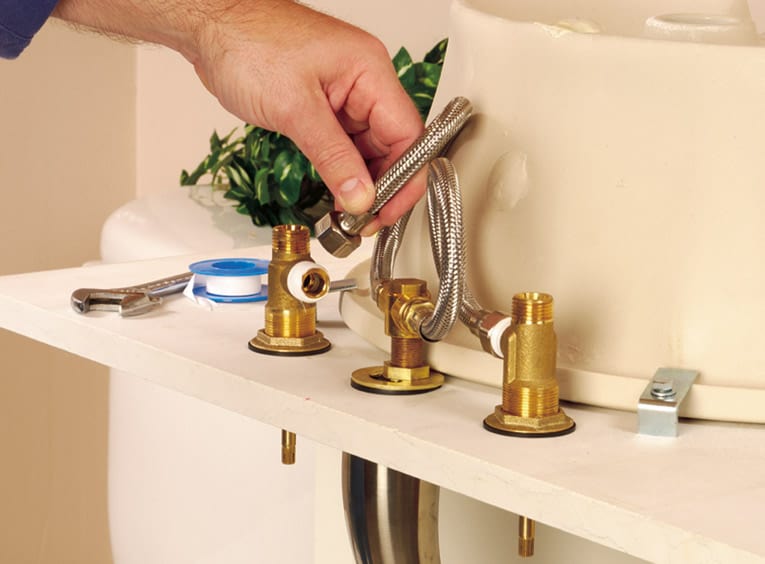 Man connecting the faucet valves to the faucet body, using flexible tubing. 