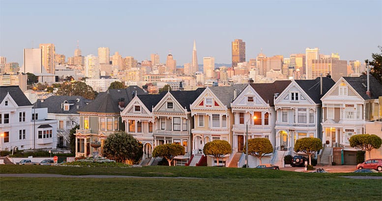 Classic Victorian houses stand proudly against a San Francisco backdrop.