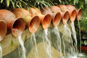 A series of ceramic pots spill water into this pond, creating a stunning waterfall.