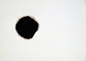 Repairing a large hole in drywall involves installing backing, then filling with spackling compound.