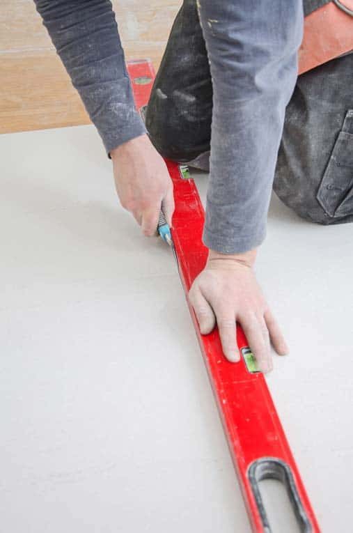Cut drywall by slicing through the surface paper with a sharp utility knife, drawing the knife along a straightedge. Snap the piece away from the cut, and then slice through the paper backing.