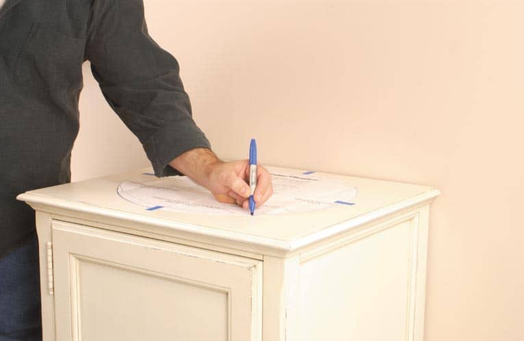 Man tracing the sink template onto the countertop with a blue marker. 