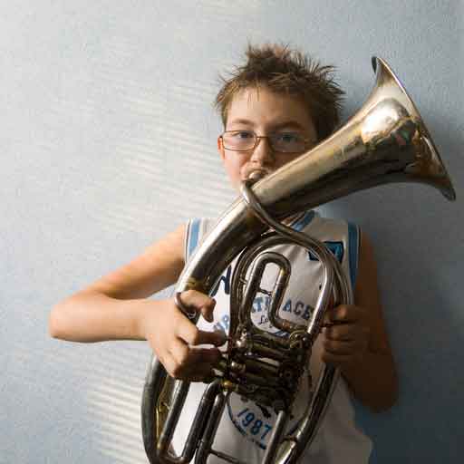 A boy blowing into a brass musical instrument.