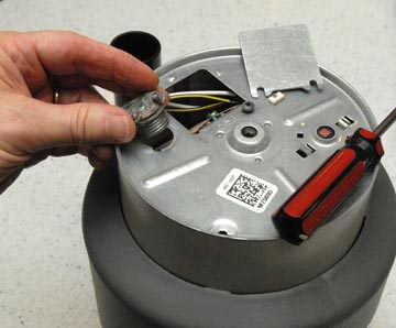 Man's hand screwing a cable clamp into a disposer unit's base.