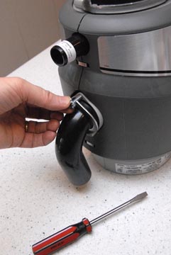 Man's hand screwing a tailpiece’s round flange to a garbage disposer unit.