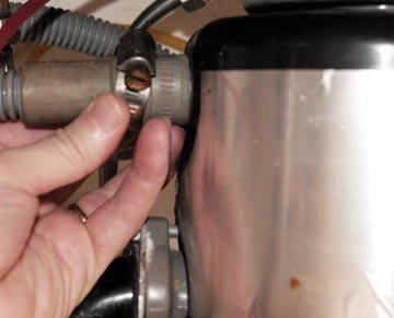 Man's hand loosening a clamp on a dishwasher's drain hose.