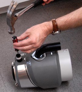 Man’s hands hammering a screwdriver to knock out a dishwasher plug.