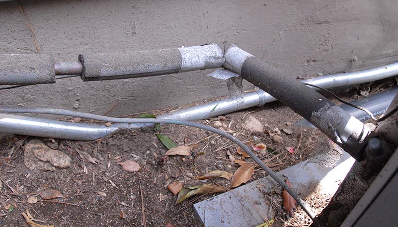 Outdoor coolant lines with missing sections of insulation. 