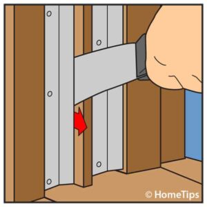 Diagram of a man’s hand prying up window weather stripping tips using a putty knife.