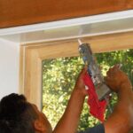 A man applying caulk on a window molding.