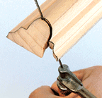 Man’s hand cutting a marked curve using a coping saw.