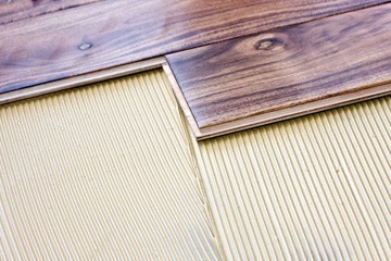 Dark shade, wide plank engineered wood flooring above an underlayment.