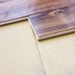 Dark shade, wide plank engineered wood flooring above an underlayment.