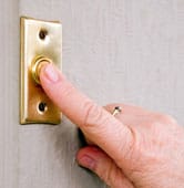 Man’s finger pressing a metallic doorbell button.