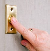 how_doorbell_works_dt1 Man’s finger pressing a metallic doorbell button.