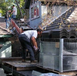 Conveyor belt delivers concrete tile roofing from truck bed to rooftop.