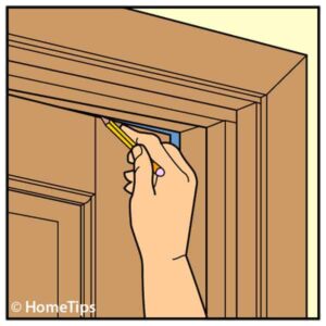 Illustration of a man's hand, marking a door's top rail using a pencil.