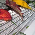 A stainless-steel, micro-mesh gutter screen in ribbed design, blocking the fallen leaves.