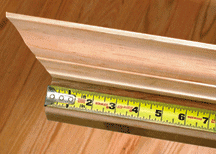A steel tape with an end hook, measuring a crown molding's length.