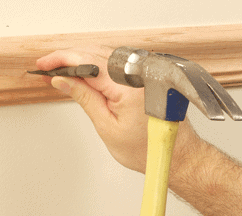 nailing_wall_trim Man's hands hammering a nailset through a molding.