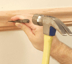 Man's hands hammering a nailset through a molding.