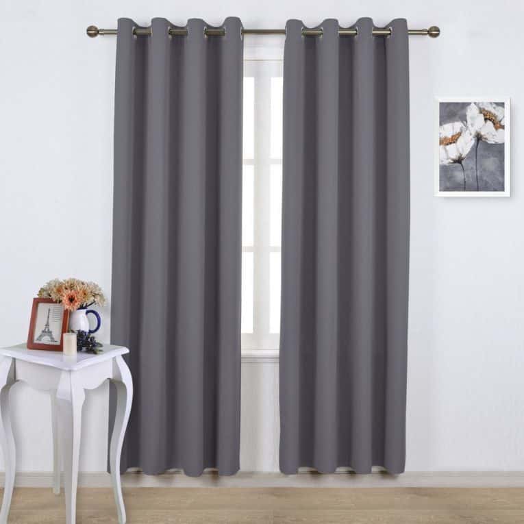 Noise reducing curtains hanging over windows in a bright room.