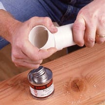 Man's hands connecting an elbow and pre-cut pipe.