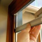 Man's hand pulling down a retractable window screen.