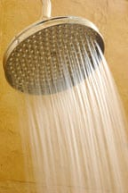 Water coming out from a large water softener shower head.