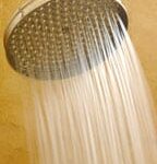 Water coming out from a large water softener shower head.