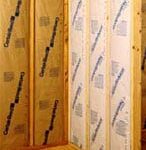 Kraft-faced insulation batts between studs of a corner interior wall.