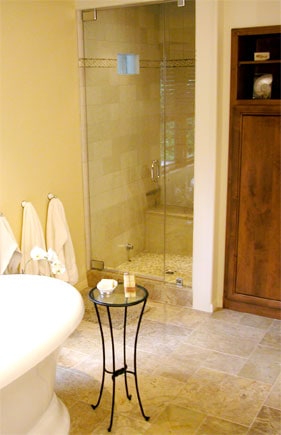 An all-glass steam shower door at the corner of a bathroom.