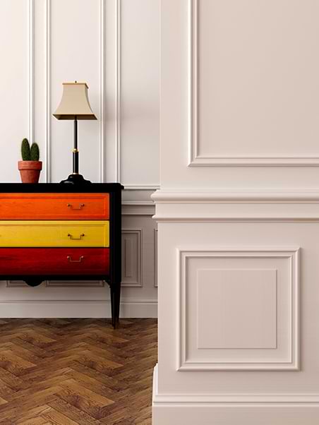 White wall wainscoting and a colorful dresser.