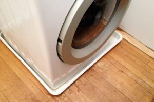 Plastic tray below the front-loading washing machine.