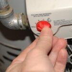 A hand adjusting a water heater temperature control dial.