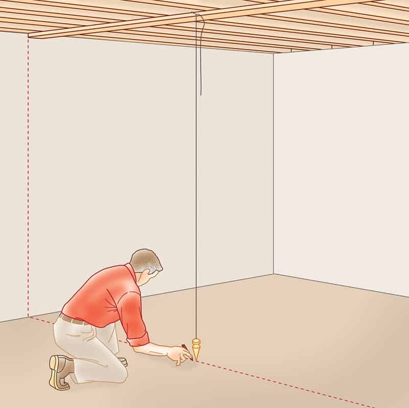 A man marking the floor below the line-up point of a hanging plumb bob.