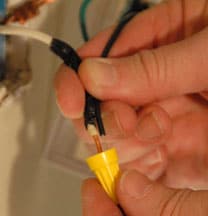 Man's fingers fastening electrical wires with a wire nut. 