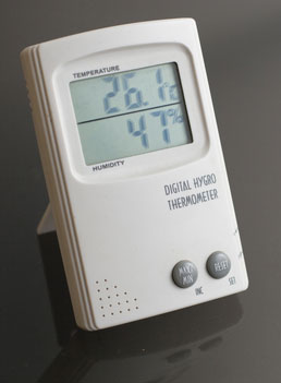 Un higrotermómetro digital blanco sobre un fondo negro.