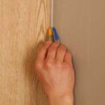 Man’s hand marking the corner edge of a panel.