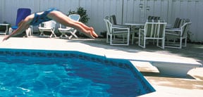 person diving off of swimming pool jump board