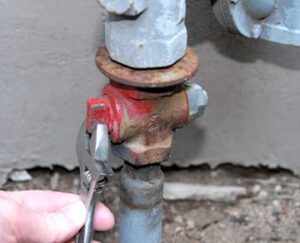 Hand and wrench turning off a home's gas supply valve. 