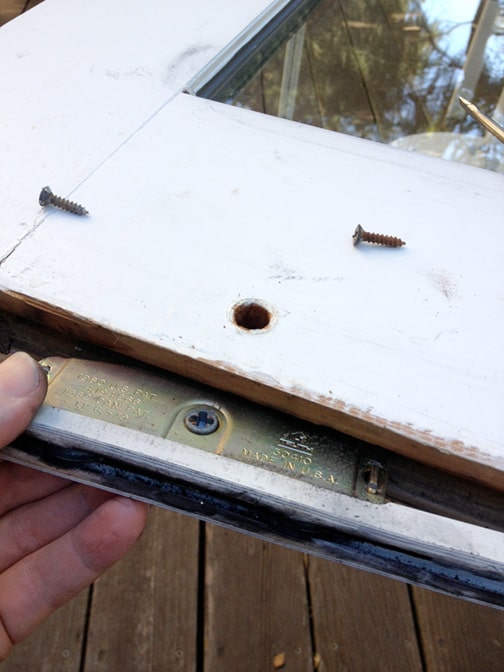 Man's hand pulling out a roller at a sliding door’s bottom.