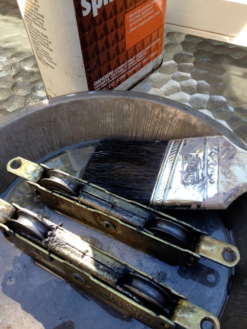 A paintbrush including two dirty sliding door rollers in a basin.