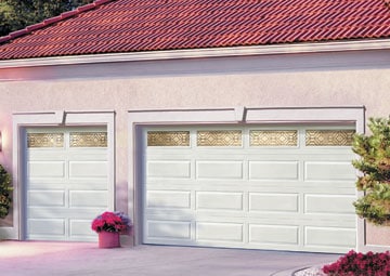 White steel double door garage with raised panel design and gold decorative window frames including a pot of pink flowers.