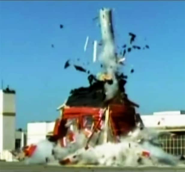 A water heater launching through the roof of an outdoor shed, with debris flying everywhere. 