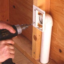 Man's hand screwing a wall-mounting bracket against a stud.