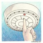 Illustration of a finger pressing the red button on a ceiling-mounted smoke detector.