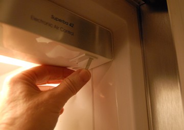 Man's hand pressing the light switch of the refrigerator door light.